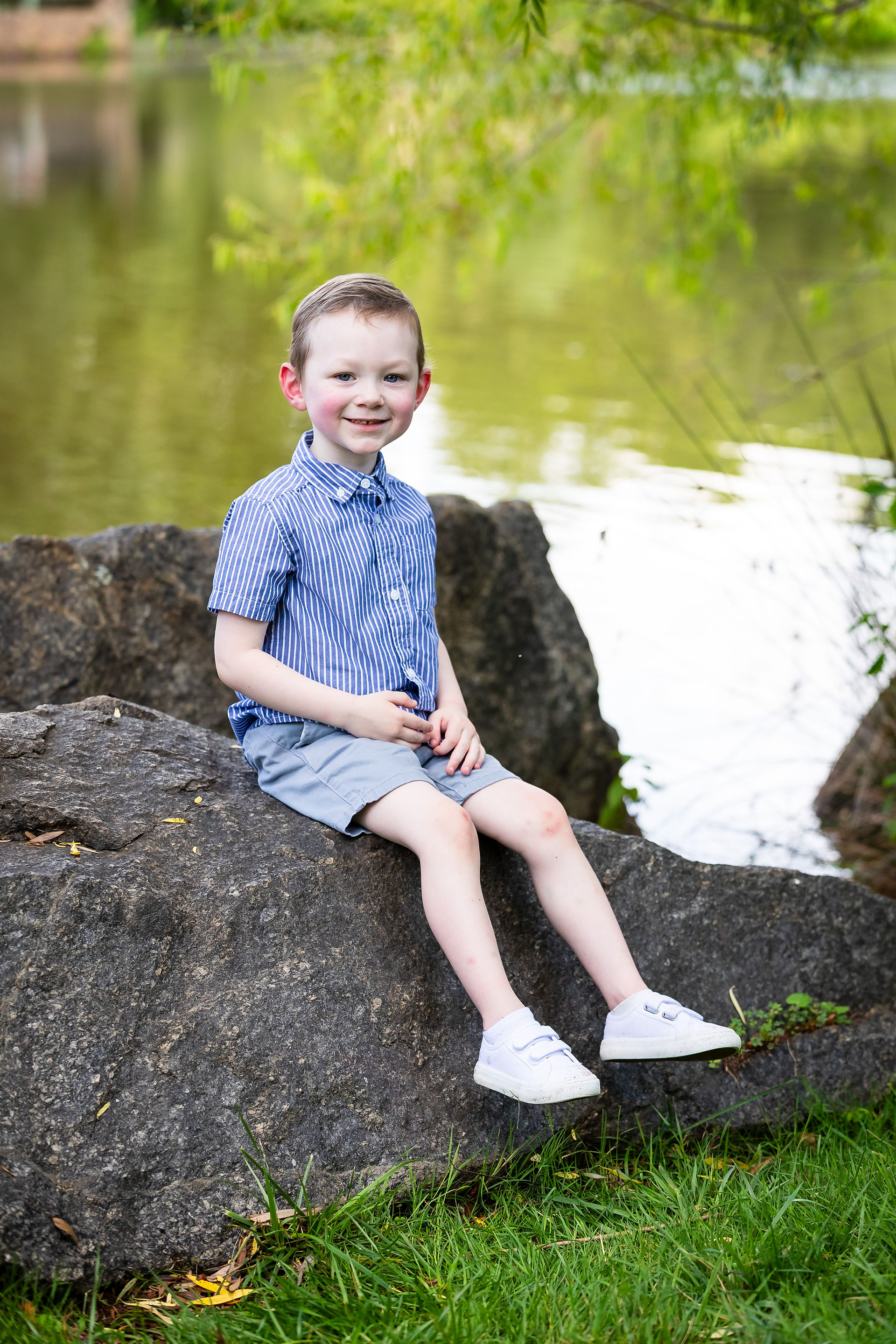 ASK Kourageous Kid Braddock Sitting on a rock at a pond.