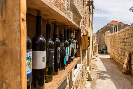 Wooden shelf with wine bottles outside of a traditional stone house
