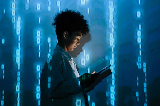 Shadow IT: A young person standing in front of a digital screen filled with binary code, looking at a tablet, symbolizing cybersecurity, data management, or technology monitoring.