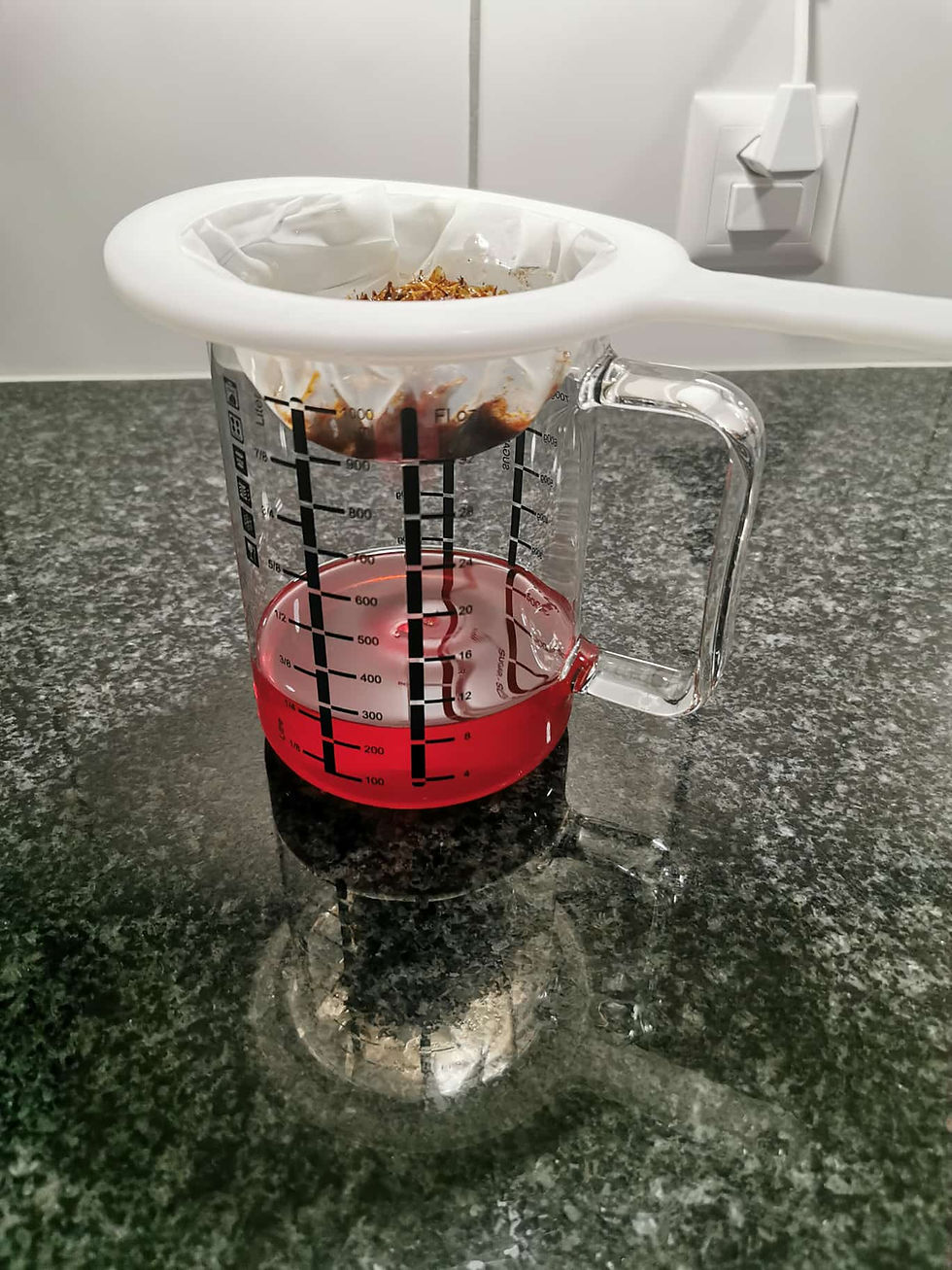 Messbecher mit roter Flüssigkeit und Sieb auf dunkler Küchenarbeitsplatte neben Lichtschalter.