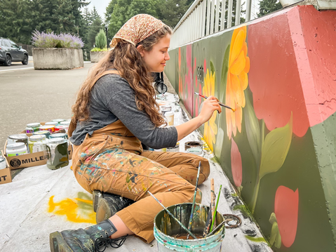 Artist Ana Gabriela painting a floral mural on the Flower Bridge in Vancouver, Washington, using Miller Paint and vibrant colors inspired by native plants