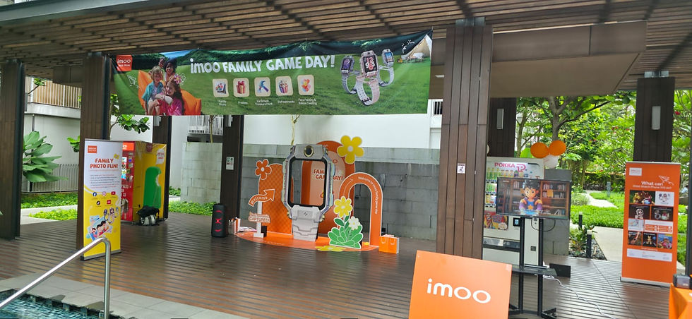 Emcee Singapore - Families gather for an exciting day of activities at the "imoo Family Game Day" event, featuring photo fun, games, and informative displays about smartwatches, all set in a vibrant, outdoor venue.