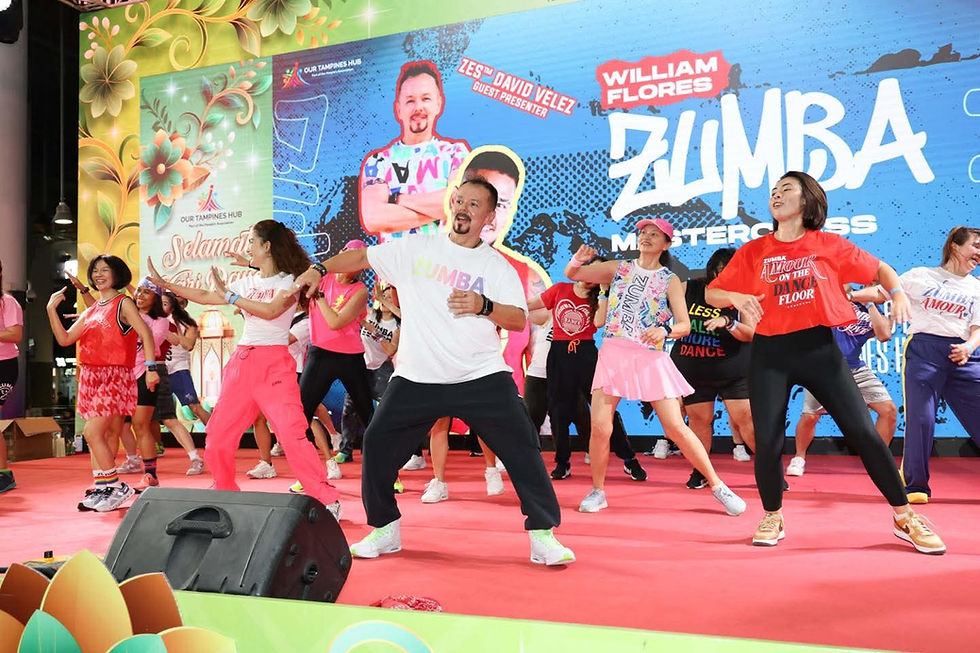 Emcee - A vibrant Zumba masterclass led by David Velez energizes participants on stage at Our Tampines Hub, with colorful attire and lively movements creating an exciting atmosphere.
