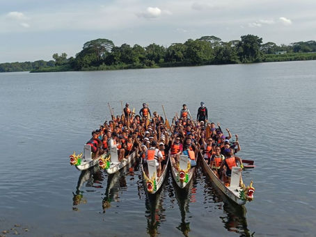 Emcee - The dragon boat racers of Safran prepared for a thrilling practice session on the serene lake with each team donning life jackets and paddles, ready to synchronize their efforts under the clear sky.