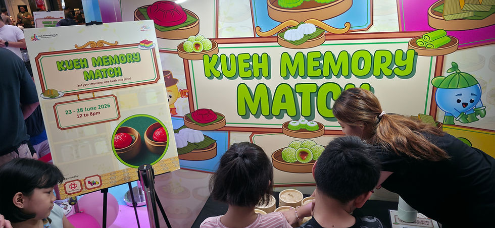 Emcee - Children participate in the "Kueh Memory Match" game at a lively event, enthusiastically testing their memory skills with colorful kueh images. The event, hosted at Our Tampines Hub, runs from June 23 to 28, 2026.