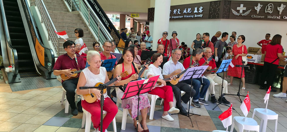 Emcee Singapore - A community band by The Friend Space performs lively tunes in Tampines Mart, surrounded by Singapore flags and onlookers, creating a festive atmosphere at our SG60 Durian Party event.