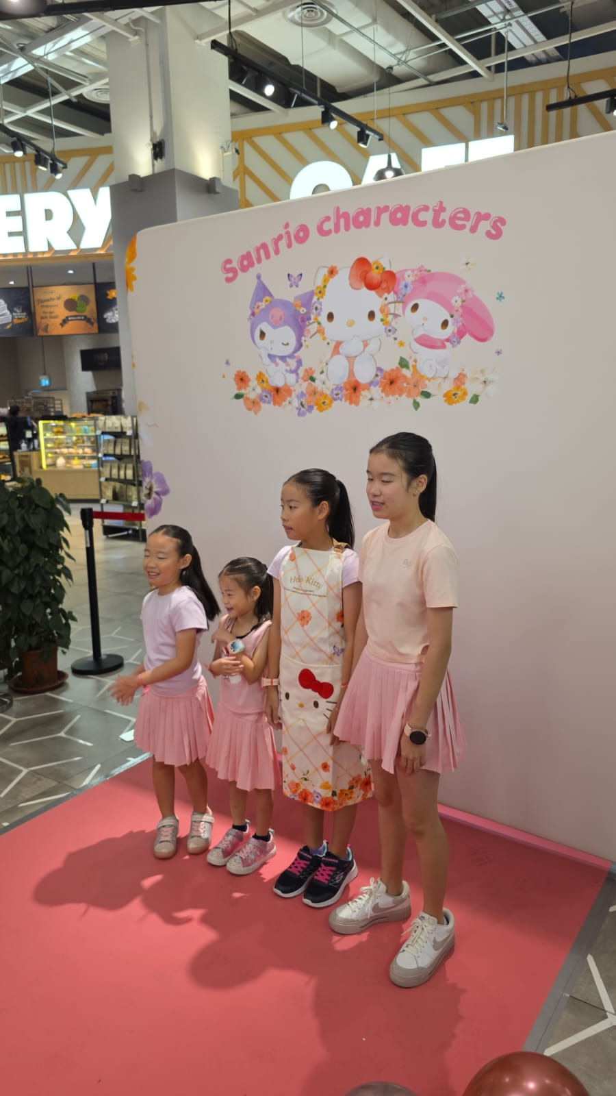 Emcee Singapore - Children pose joyfully in front of a colorful Sanrio character backdrop, embracing the playful atmosphere with matching outfits and cheerful expressions.