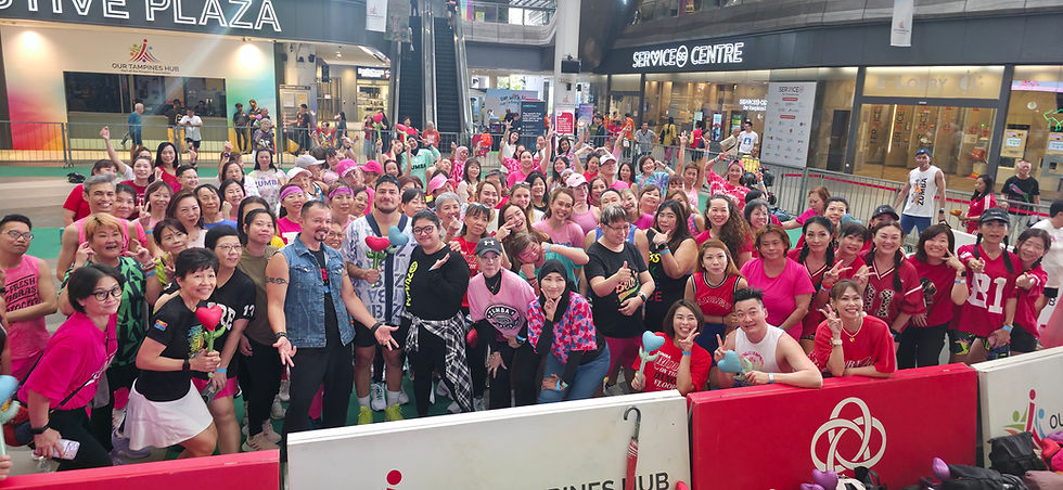 Emcee - A vibrant group gathers at Our Tampines Hub in festive attire, radiating joy and excitement for a lively Zumba event.