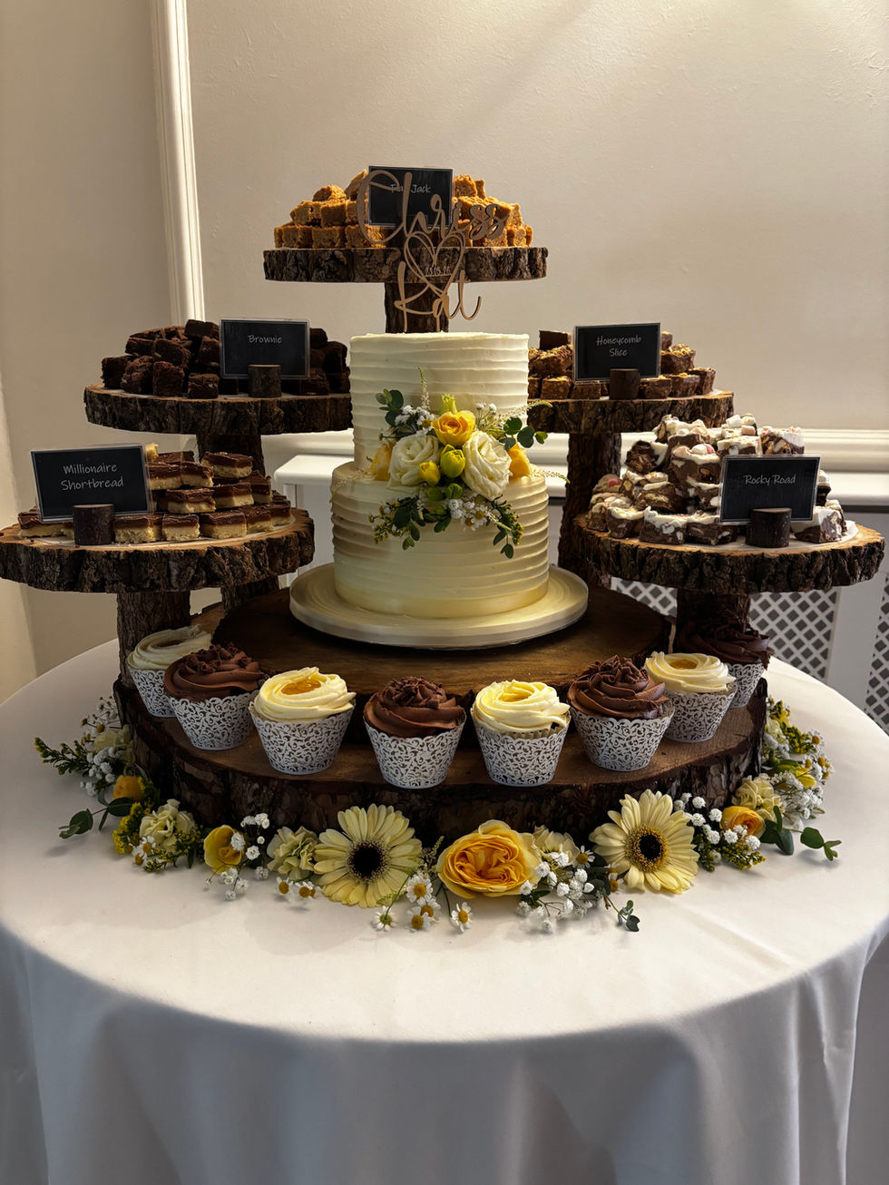 Elegant cake display with cupcakes and floral decorations.