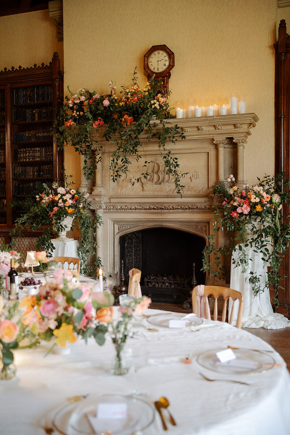 Elegant dining room with a flower-draped fireplace, candles, and set tables, creating a warm formal banquet mood.