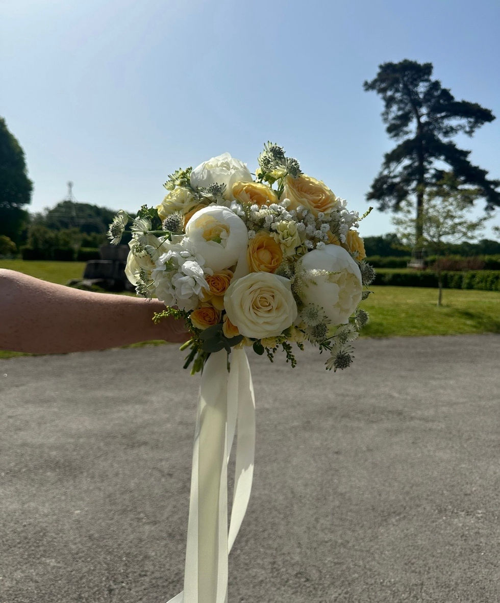 Bouquet of white and yellow flowers held outdoors.