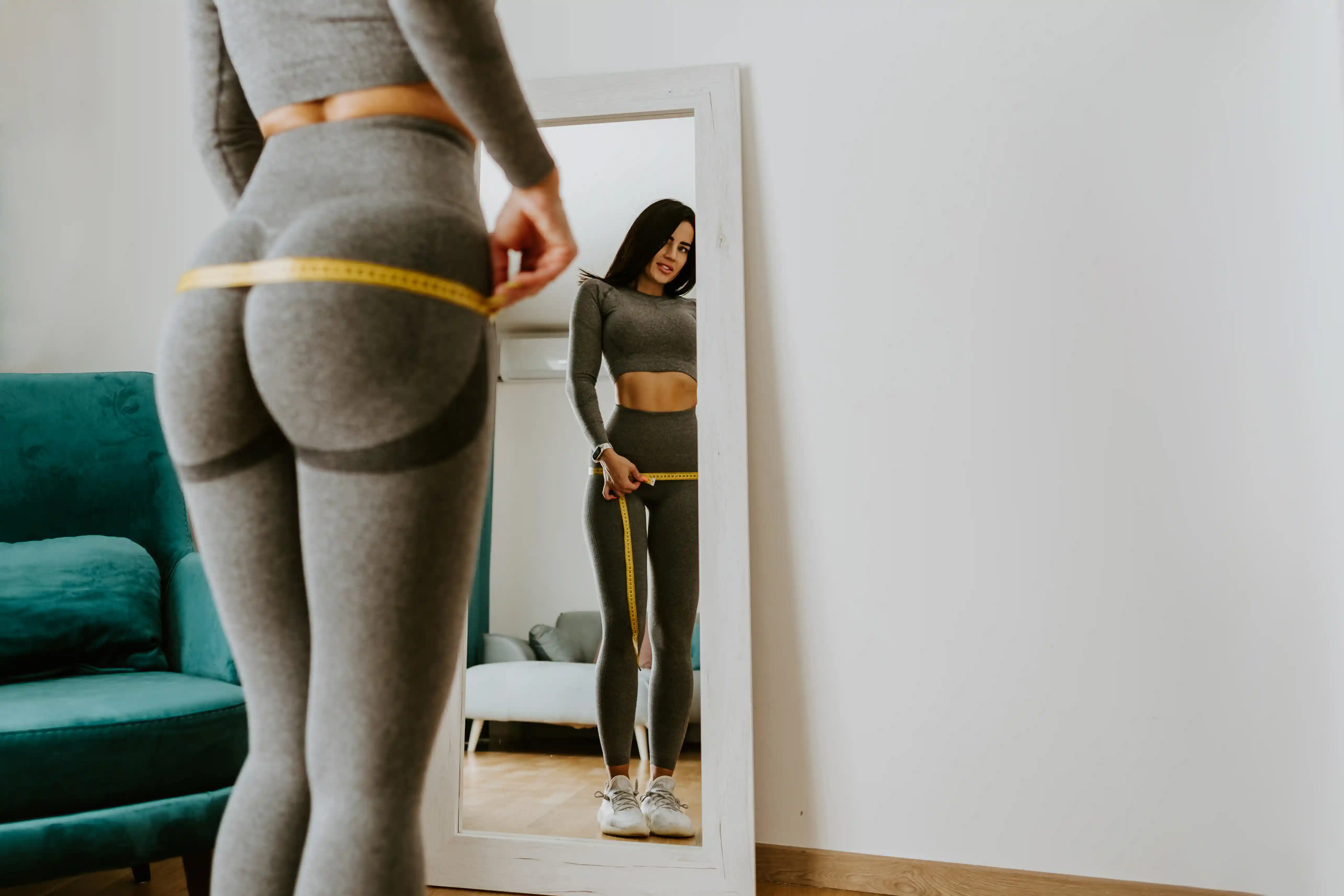 fitness-woman-measuring-butt-with-tape-at-home-st-2021-09-02-22-25-35-utc.webp