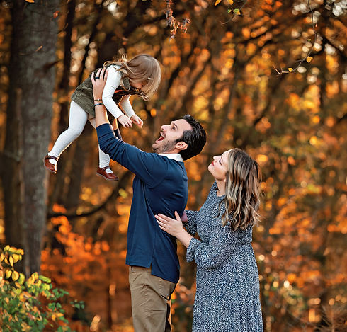 Happy family portrait: Dad playfully lifts daughter, autumn leaves