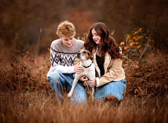 Teenage boy and girl crouched beside a dog, both looking at it affectionately during a family session in Atlanta, Georgia”