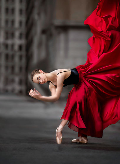 Ballerina in red flowing dress dancing against urban Atlanta backdrop