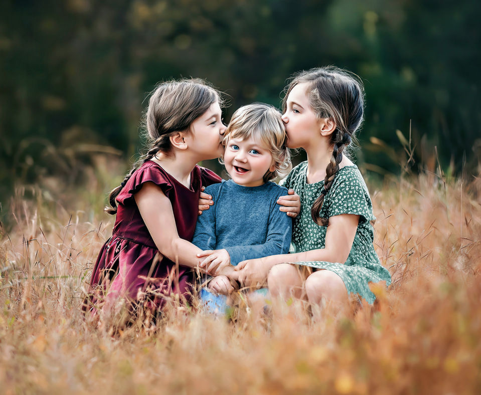 little siblings in a field of tall grass