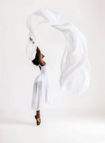Dancer in white dress with flowing silk during a photoshoot.