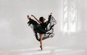 ballerina doing an arabesque next to a window