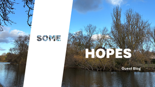 A river in winter. Trees line the bank. The sky is bluw with white clouds