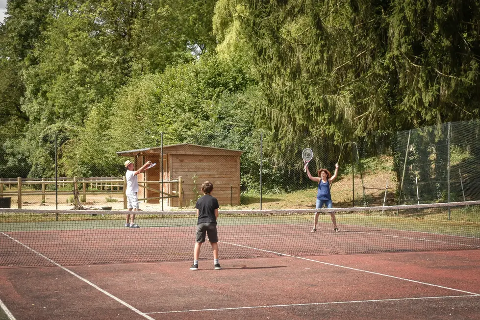 Scène de tennis entre campeurs : photographe animation camping | activité sportive familiale en extérieur