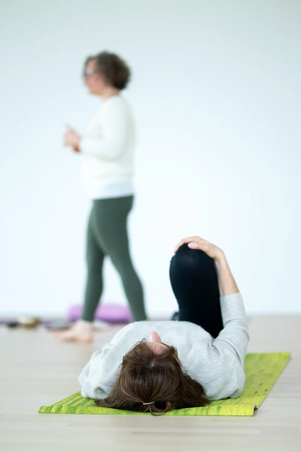 Photographe professionnel pendant un cours de yoga avec professeure guidant les élèves en posture.