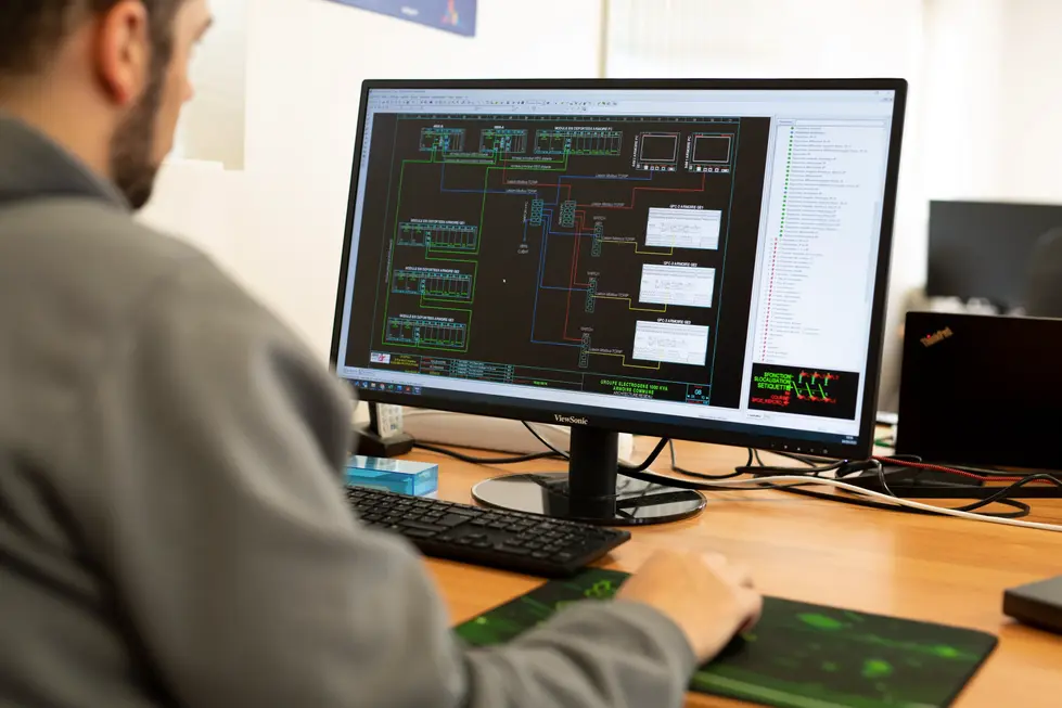 Photo d’un collaborateur devant son écran avec un plan technique : Photographe professionnel en entreprise | technicien ARPEE travaillant sur un schéma électrique