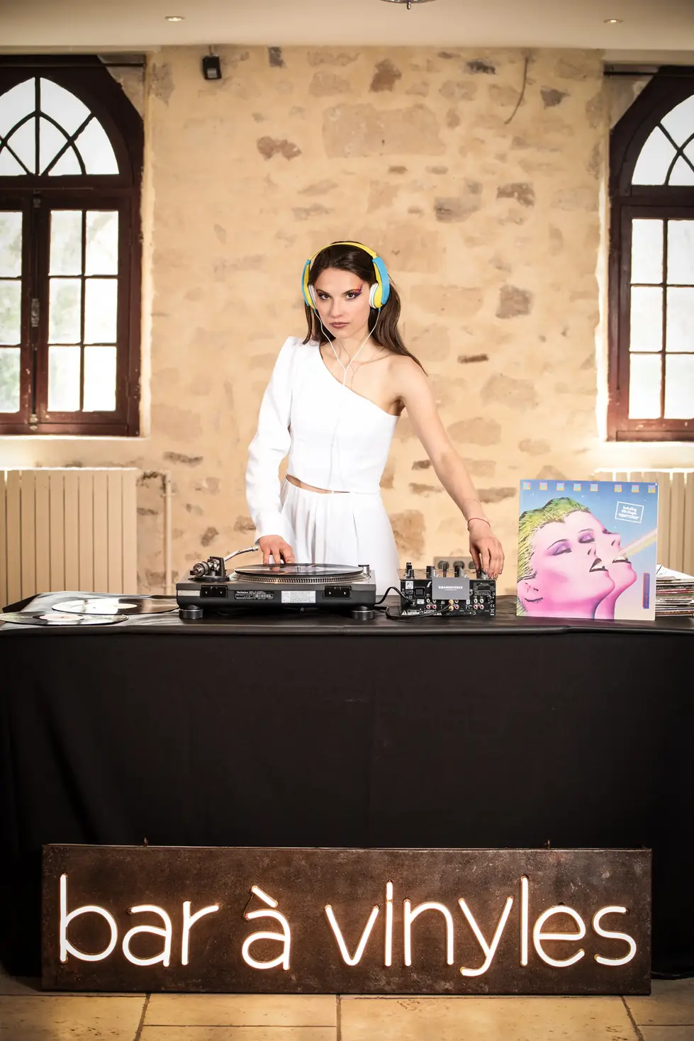 DJ femme au bar à vinyles : photographe création artistique | tenue blanche et scène musicale décalée