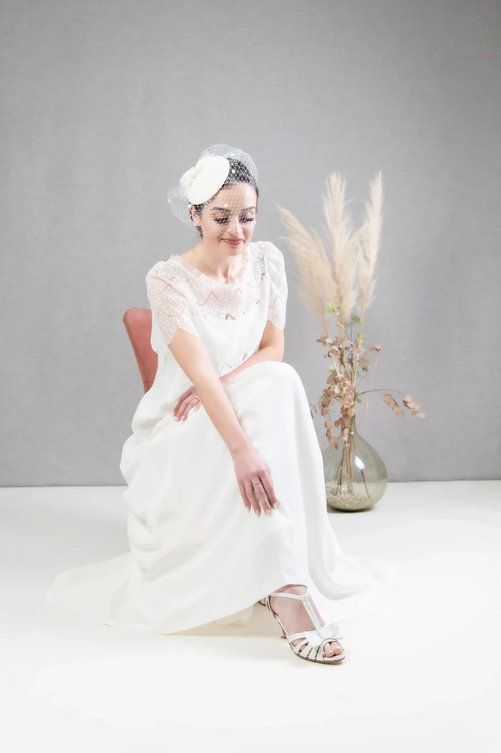 Mariée assise, robe en dentelle et voilette rétro – ambiance douce et raffinée en studio par Fred Photo.