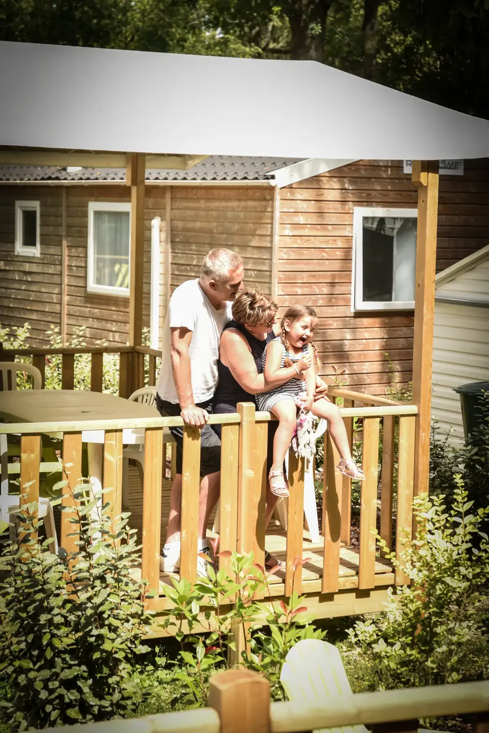 Famille sur la terrasse d’un mobil-home : photographe entreprise touristique | moment complice en mobil-home en pleine verdure