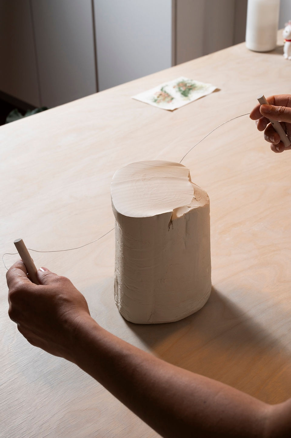 Alice slicing a porcelain block with a cutting wire, beginning the slab-building process.