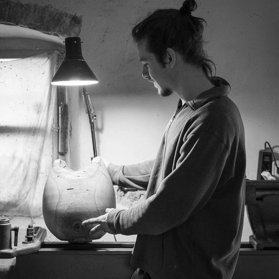 The designer Lorenzo Cappellini is holding one of his works under the light of a lamp. He is inside his own studio.