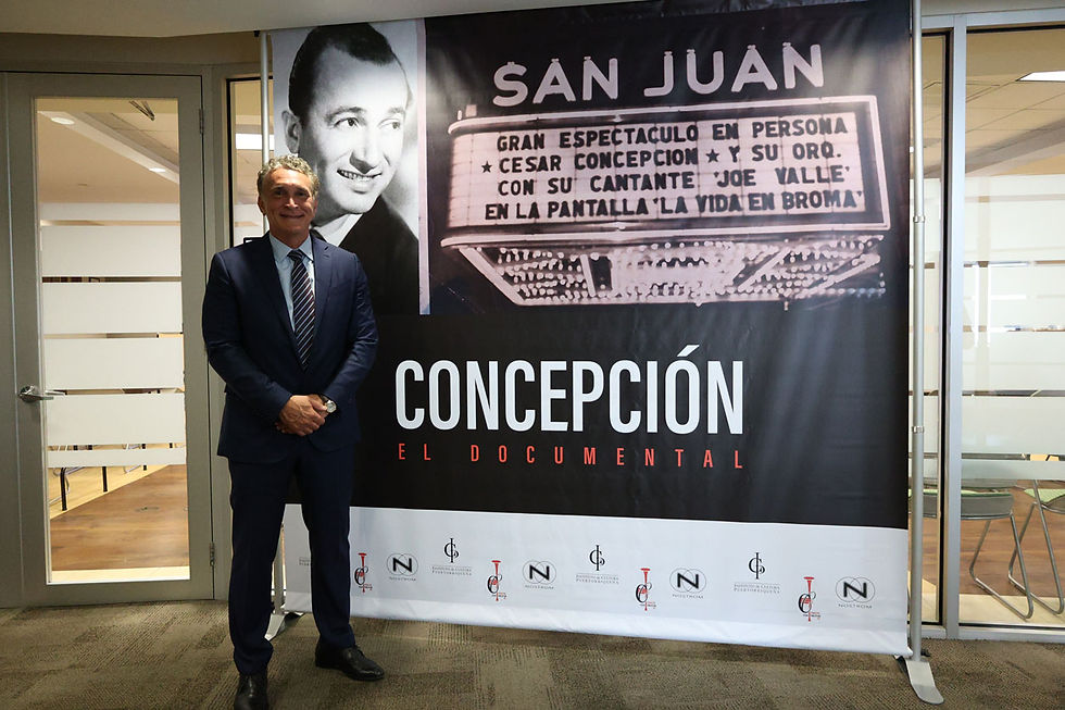 César Concepción De Peña (Hijo) junto al afiche del documental César Concepción, El Trompetista.