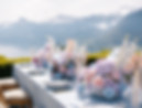 A beautifully decorated table with flowers and cutlery overlooking mountains
