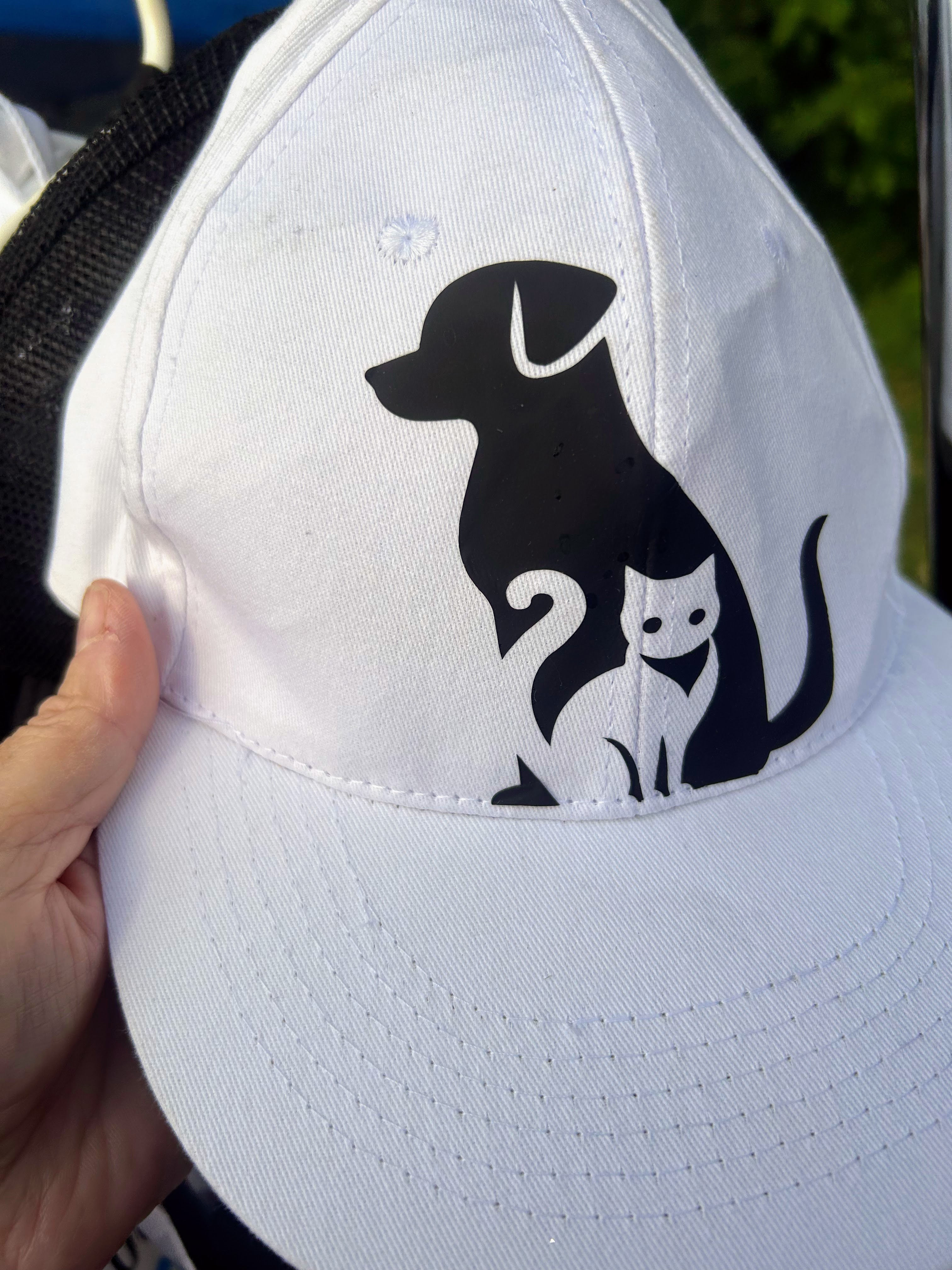 white cap with black dog outline and white cat in front