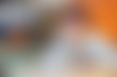 Older woman sitting at a table holding a phone and thinking.