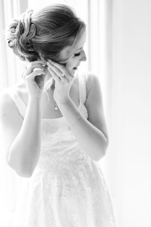 Elagent black and white photo of bride putting in her earrings