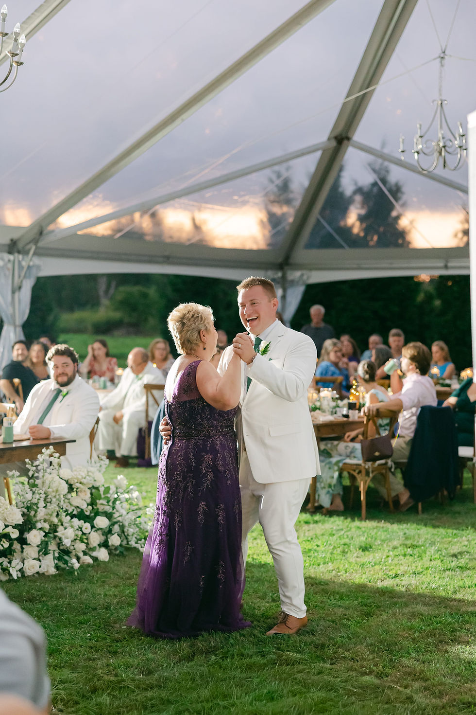 Mother son dance at wedding reception with guests watching under tent in Michigan