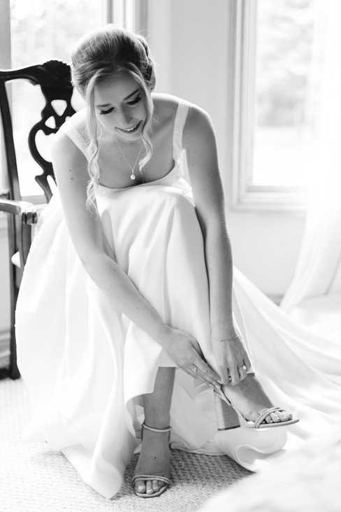 Elegant bride putting on designer wedding shoes