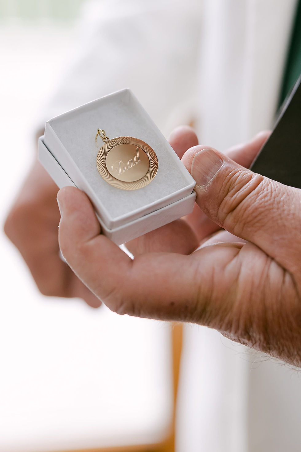 Bride gifting her father a personalized pendant during emotional first look