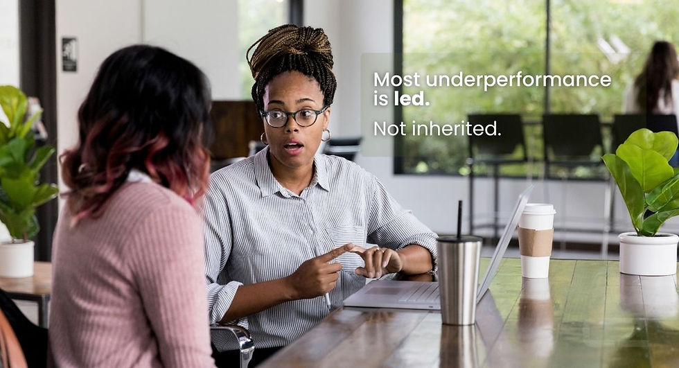 Two women sit at a table with laptops and coffee, engaged in conversation. Text reads: "Most underperformance is led. Not inherited."