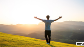 Man with arms outstretched stands on a grassy hill at sunrise, overlooking mountains. Sky is bright; mood is joyful. "CZ" logo in corner. Craig Zuber's Weekly Edge