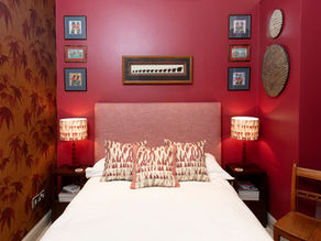 red walls, red bed head, African print cushions and lamps