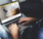 An adult sitting and working on a laptop computer, editing a website.