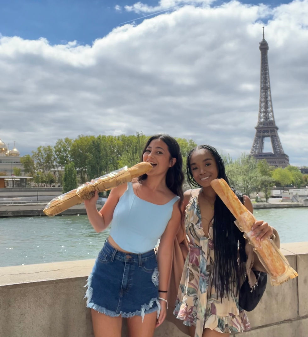 two girls eating giant baguettes in front of the river and the eiffel tower in paris, france