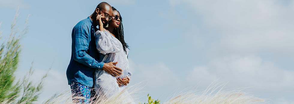 Black couple expecting a child, man embracing wife, enjoying pregnancy photoshoot in Mauritius