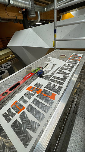 Painting the Boulderverstas logo on the climbing wall using a stencil