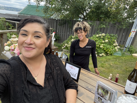 Two women smiling at an outdoor bar with a "Closed" sign