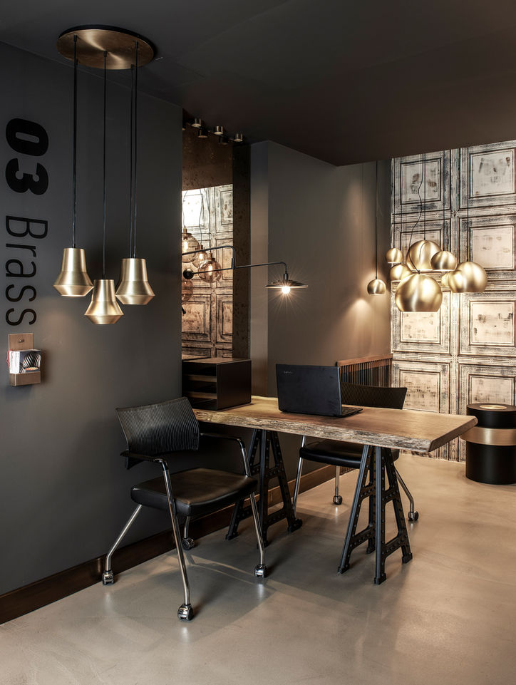 Dr-Light showroom Brass koleksiyonu bölümü siyah zemin çalışma masası sandalye sarı metalik sarkıt armatürler tasarım sergileme - DPI Group iç mimari