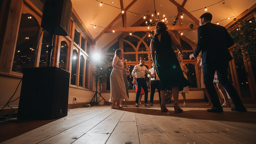 Low-angle view of wedding guests dancing beneath warm lights near a DJ speaker