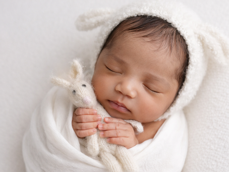 Newborn baby wrapped in soft white blanket with a cute bunny hat